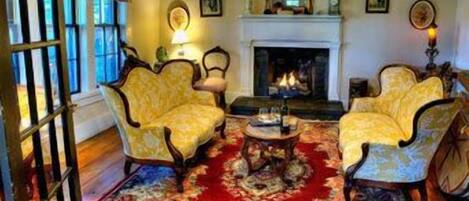 A room with two armchairs, a fireplace, and a patterned rug.