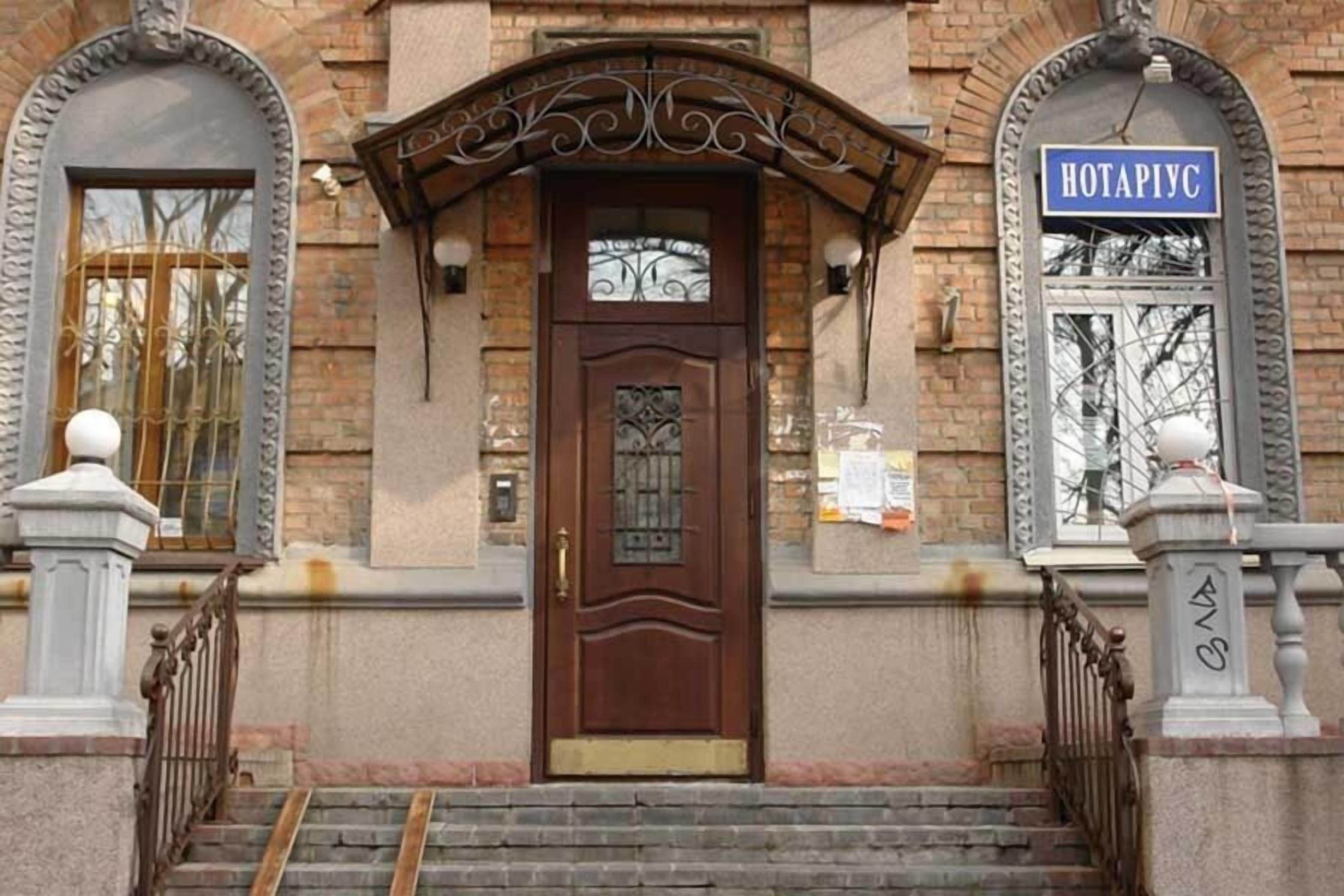 Entrada d'un edifici amb una porta marró, un rètol que diu "HOTAPIYC" i una escala que condueix a l'entrada.