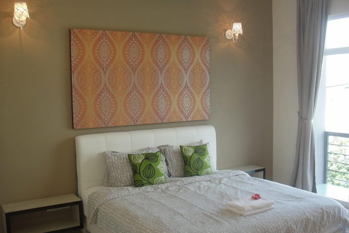 A bedroom with a large bed, a patterned wall hanging, and two wall-mounted lamps.