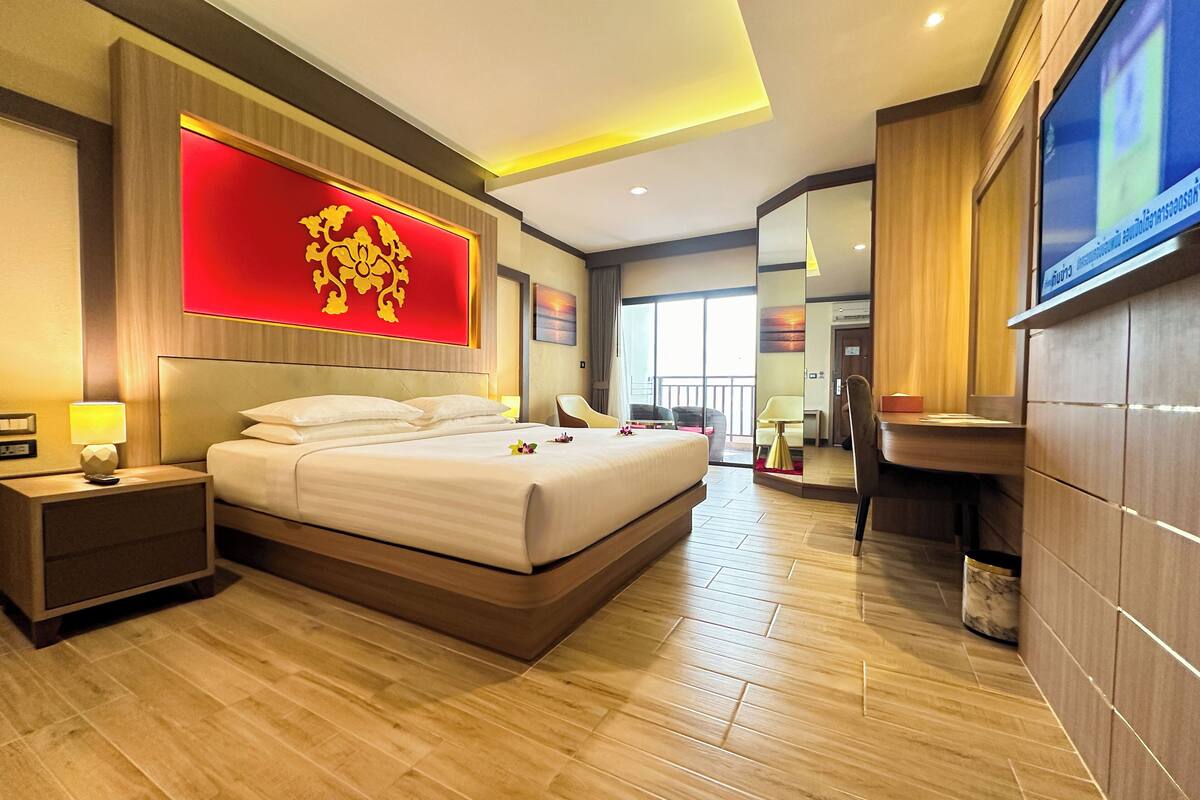 A modern hotel room with a large bed, a nightstand, a desk, and a bathroom area.
