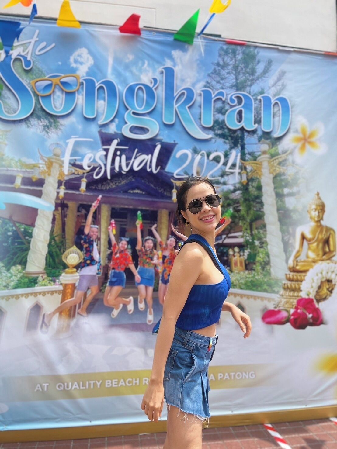 Un cartel promocional del Festival Songkran 2024, con un templo tailandés tradicional y gente vestida para la celebración.