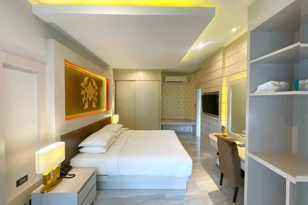A modern hotel room with a large bed, bedside tables, a desk, and a wardrobe.