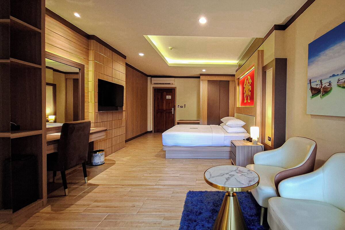 A hotel room with a bed, a desk, a chair, and a TV.