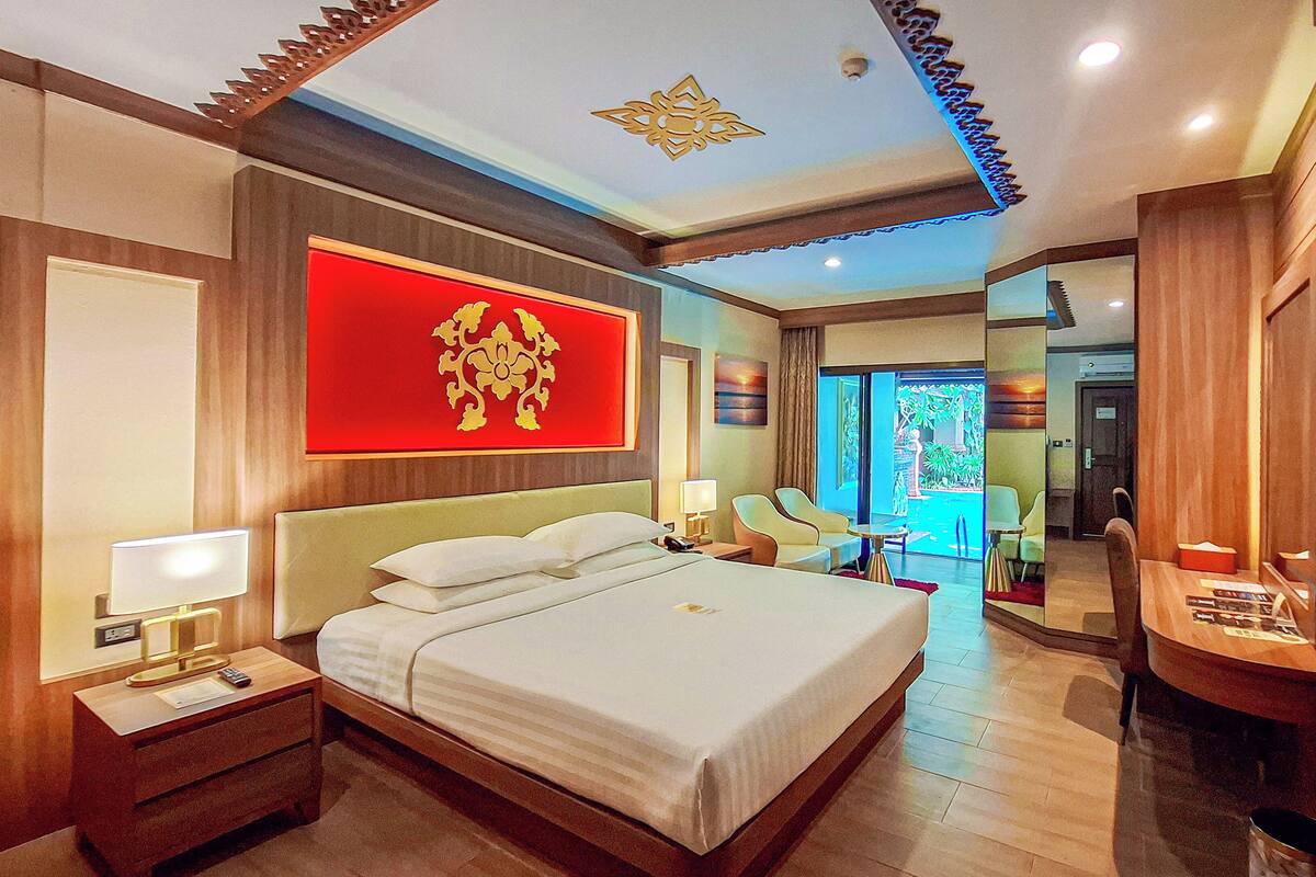 A hotel room with a large bed, a TV, and a red wall decoration.