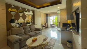 A modern living room with a sofa, coffee table, and a TV mounted on the wall. - Quality Beach Resorts and Spa Patong (Patong)