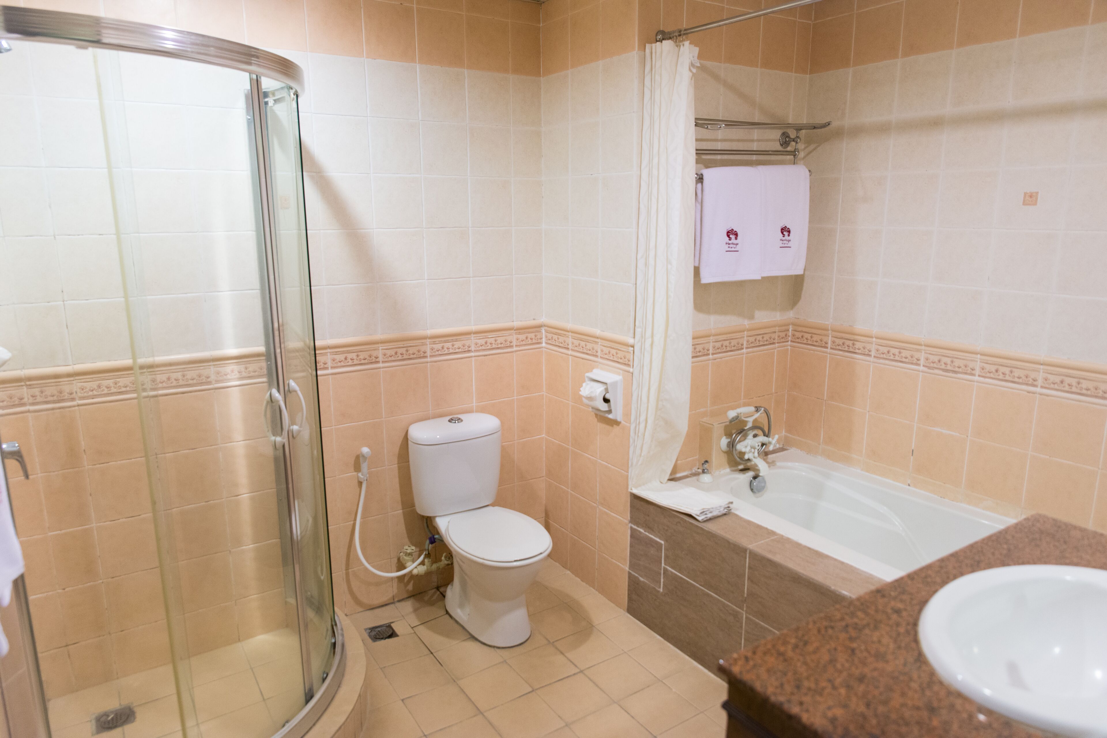 A bathroom with a glass-enclosed shower, a toilet, a bathtub, and a sink.