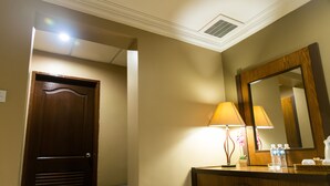 A hotel room with a wooden door, a bedside lamp, a mirror, and a small potted plant. - Heritage Hotel (Tawau)
