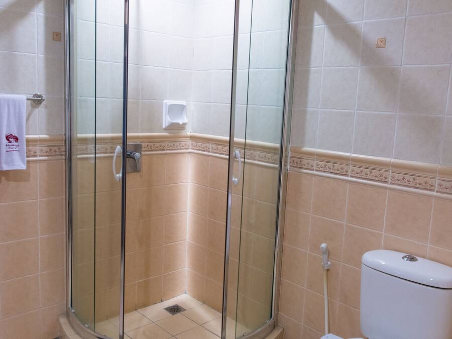 A bathroom with a glass-enclosed shower, a toilet, and beige tiled walls.