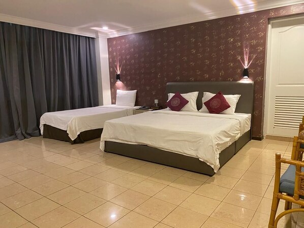 Una habitación de hotel con dos camas, una silla y un ventanal con cortinas.