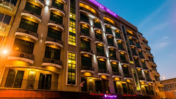 A multi-story hotel with balconies, large windows, and a neon sign indicating it is the Heritage Hotel. - Heritage Hotel (Tawau)