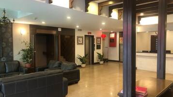 Relax in a spacious lobby with a seating area and potted plants, surrounded by a high ceiling and modern design.