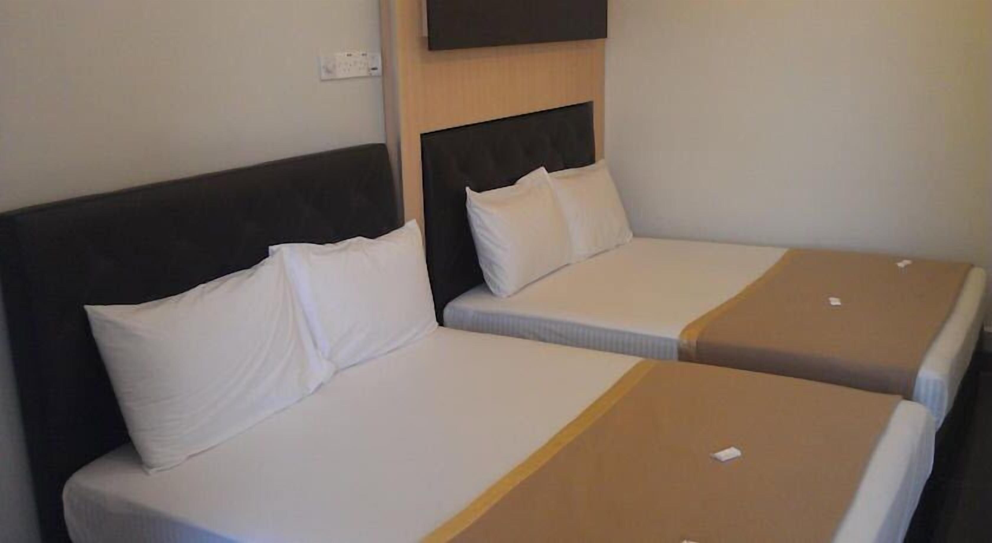 Zwei Einzelbetten mit weißen Bettwäsche und braunen Kopfteilen in einem Hotelzimmer.