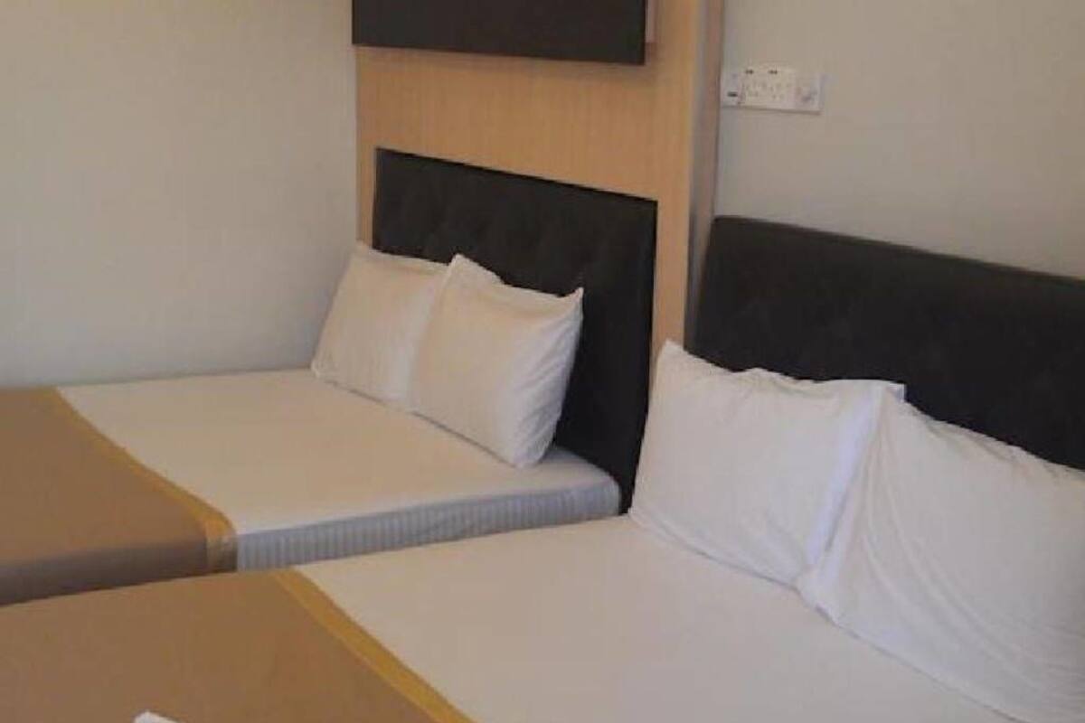 A hotel room with two beds, each with white bedding and a headboard.