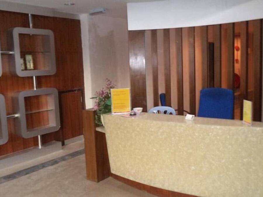 A reception area with a beige counter, blue chairs, and a wooden panel wall.