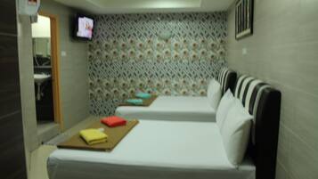 Habitación de hotel con dos camas, un televisor en la pared y un papel tapiz estampado.
