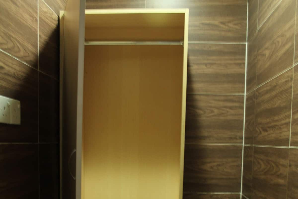 A bathroom with dark wood paneling, a white tiled floor, and a wooden shelf unit.