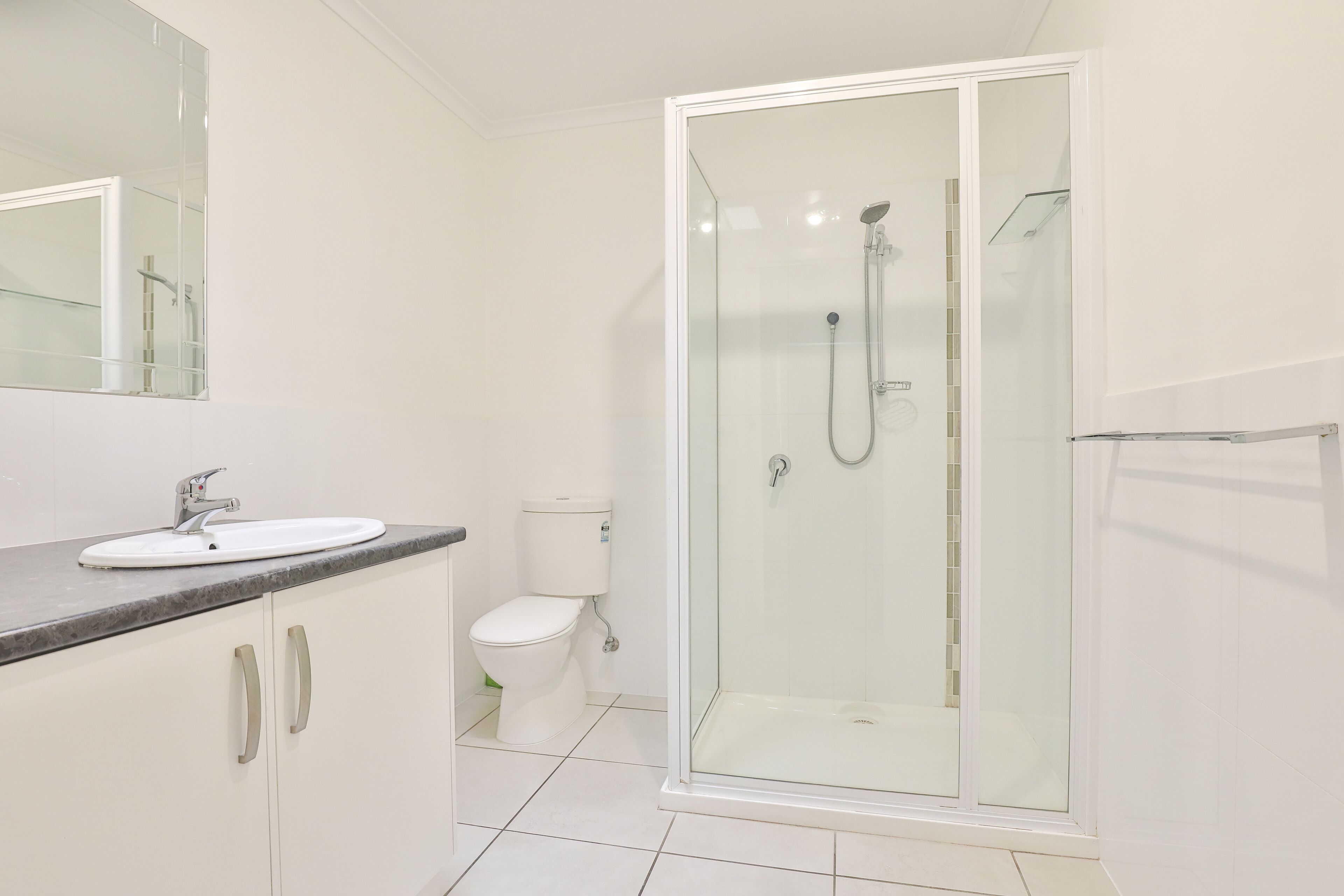 A modern bathroom with a glass-enclosed shower, a white sink with a marble countertop, and a toilet.