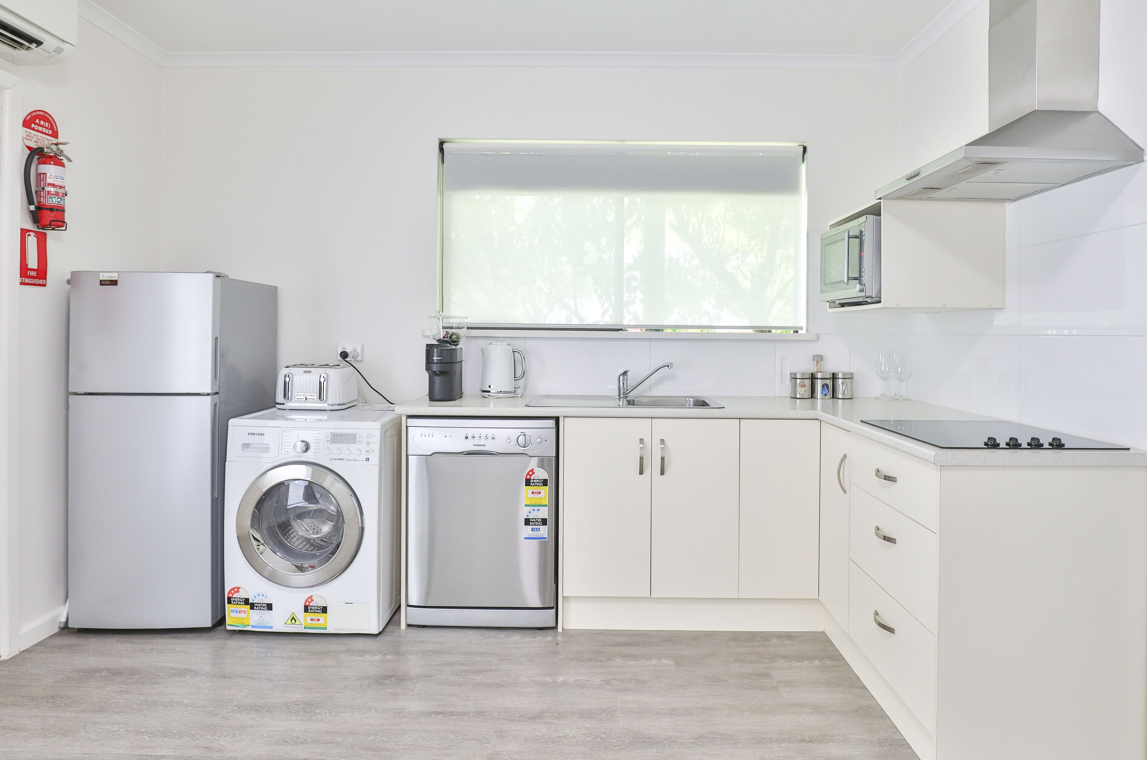 Een moderne keuken met een wasmachine, vaatwasser, magnetron en een spoelbak.