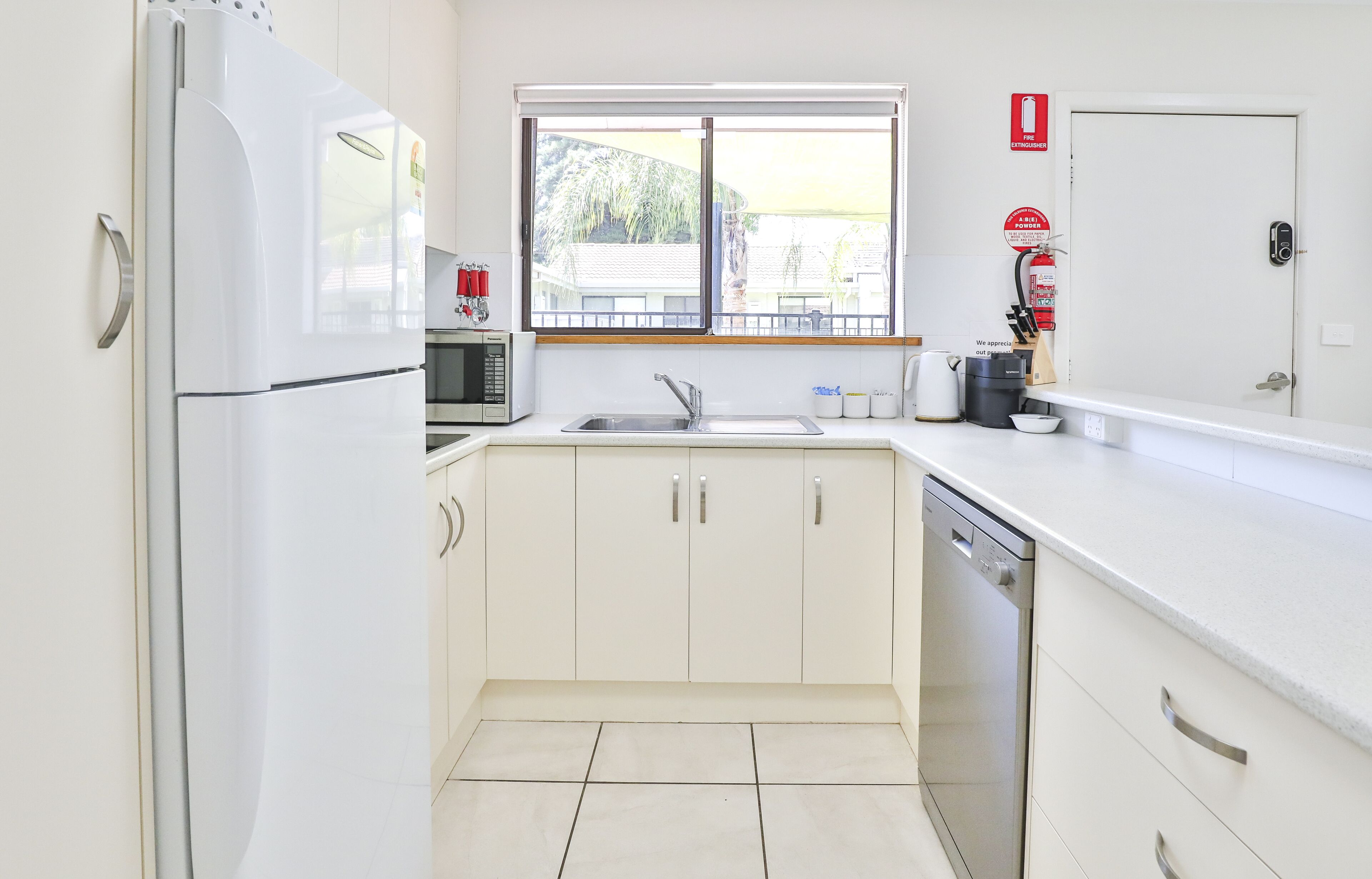 A modern kitchen with white cabinets, a stainless steel sink, and a dishwasher.
