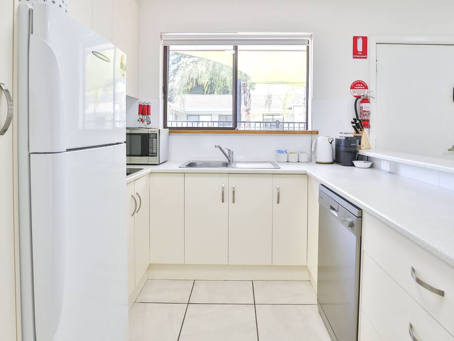 A modern kitchen with white cabinets, a stainless steel sink, and a dishwasher.
