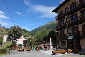 Ein Hotel mit Außenbereich, einem Bergpanorama und einem Schild, das es als Restaurant kennzeichnet.