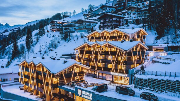 A hotel with a modern architectural design, featuring multiple balconies and a ski slope in the background. - GLEMM by AvenidA Superior Hotel & Residences (Saalbach-Hinterglemm)