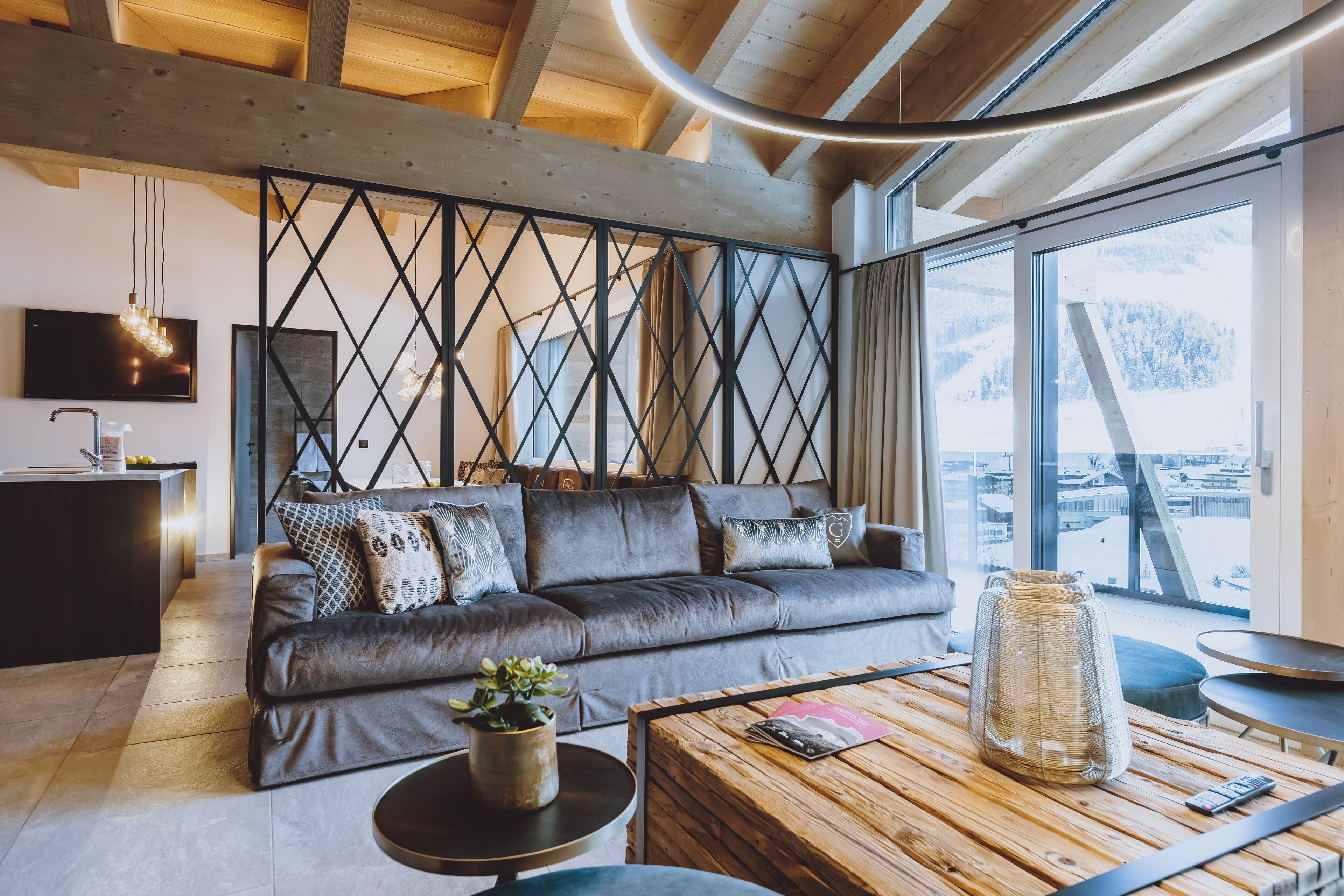 Una sala de estar moderna con un sofá de cuero, una mesa de centro de madera y un ventanal con vistas a montañas.