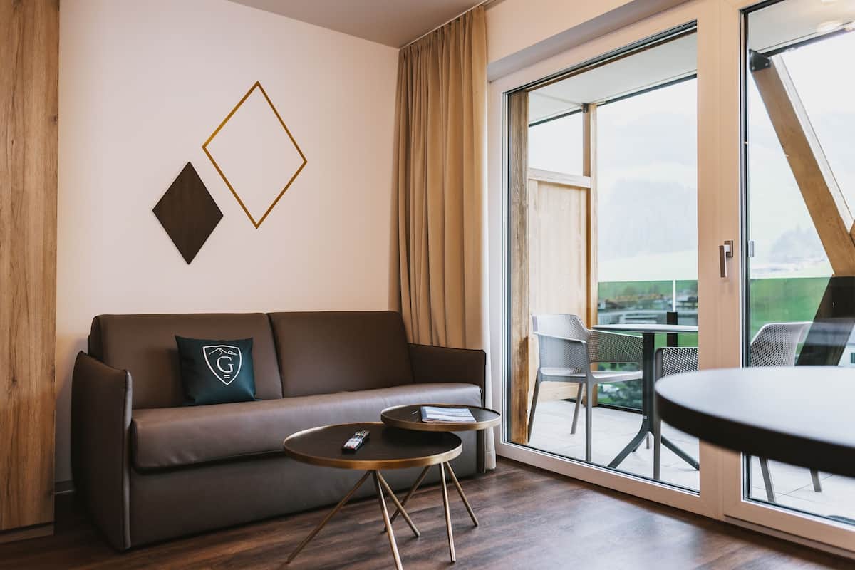 Ein modernes Wohnzimmer mit einer Couch, zwei Beistelltischen und einer großen Schiebeglastür, die zu einem Außenbereich führt.
