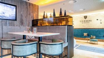 A modern interior with a dining area featuring a round table and four chairs, a sofa, and a wall-mounted display.