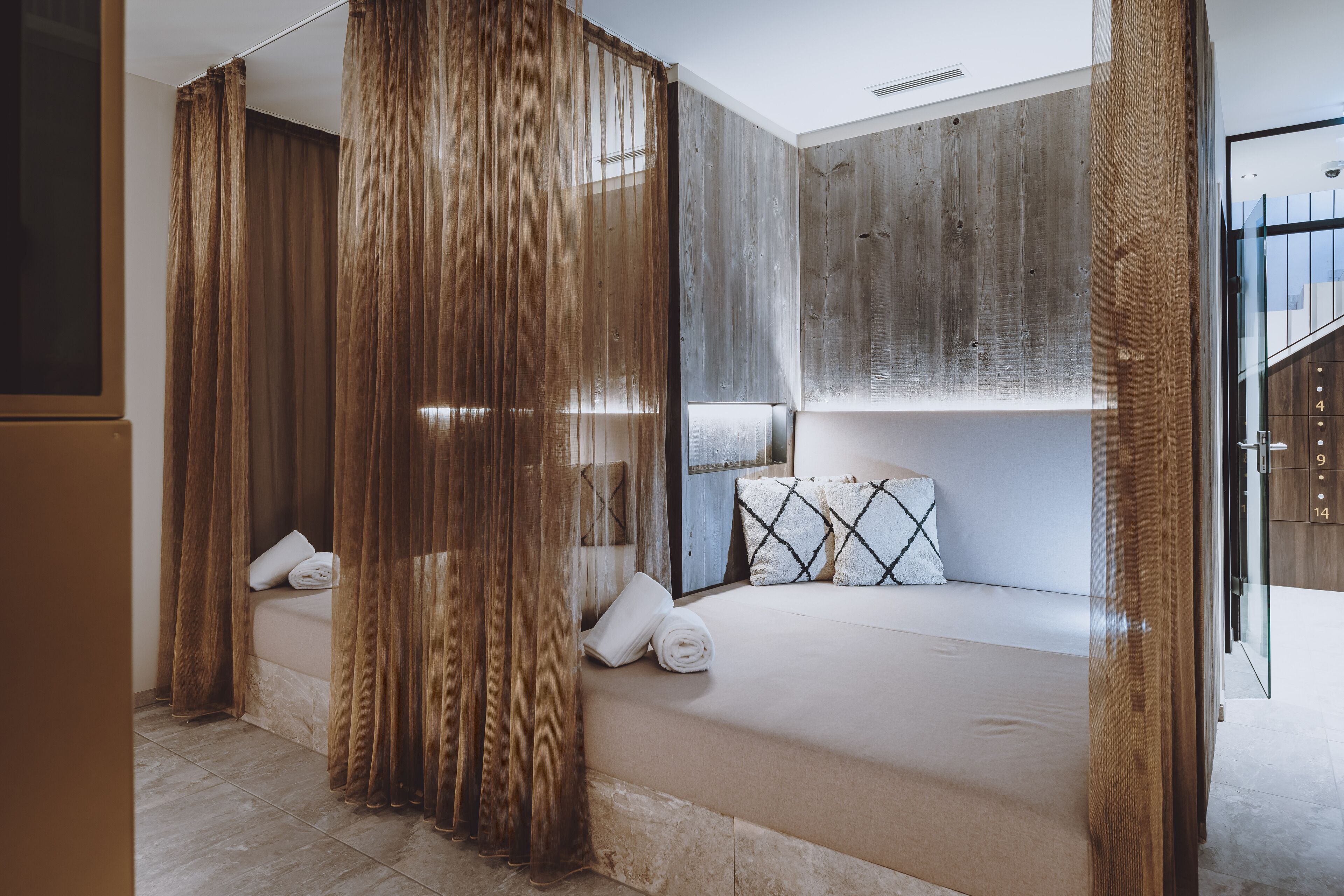 Une chambre d’hôtel moderne avec un grand lit, des murs recouverts de panneaux en bois et une vue sur l’extérieur.