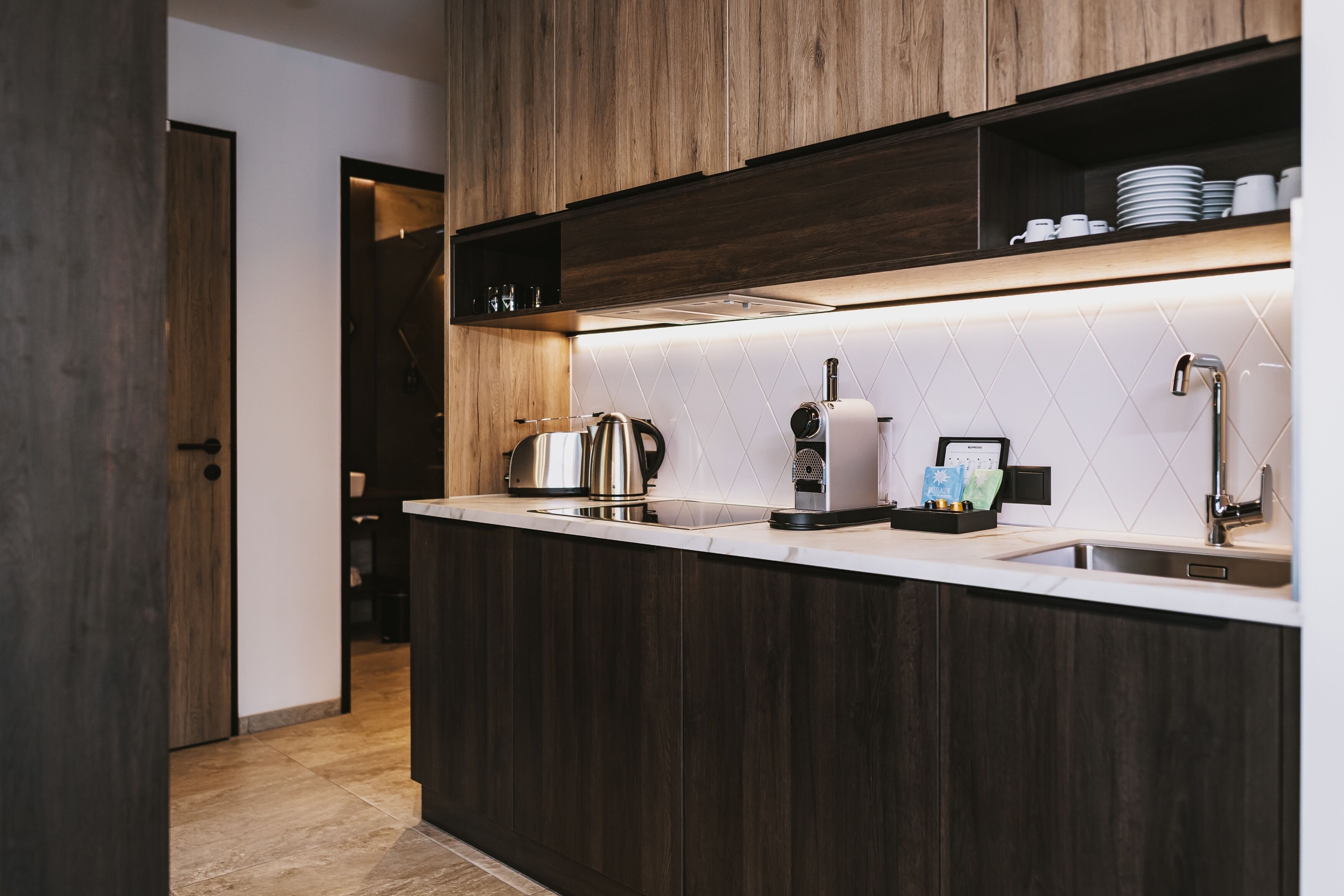 Una cocina moderna con gabinetes de madera oscura, encimera blanca y extractor empotrado.
