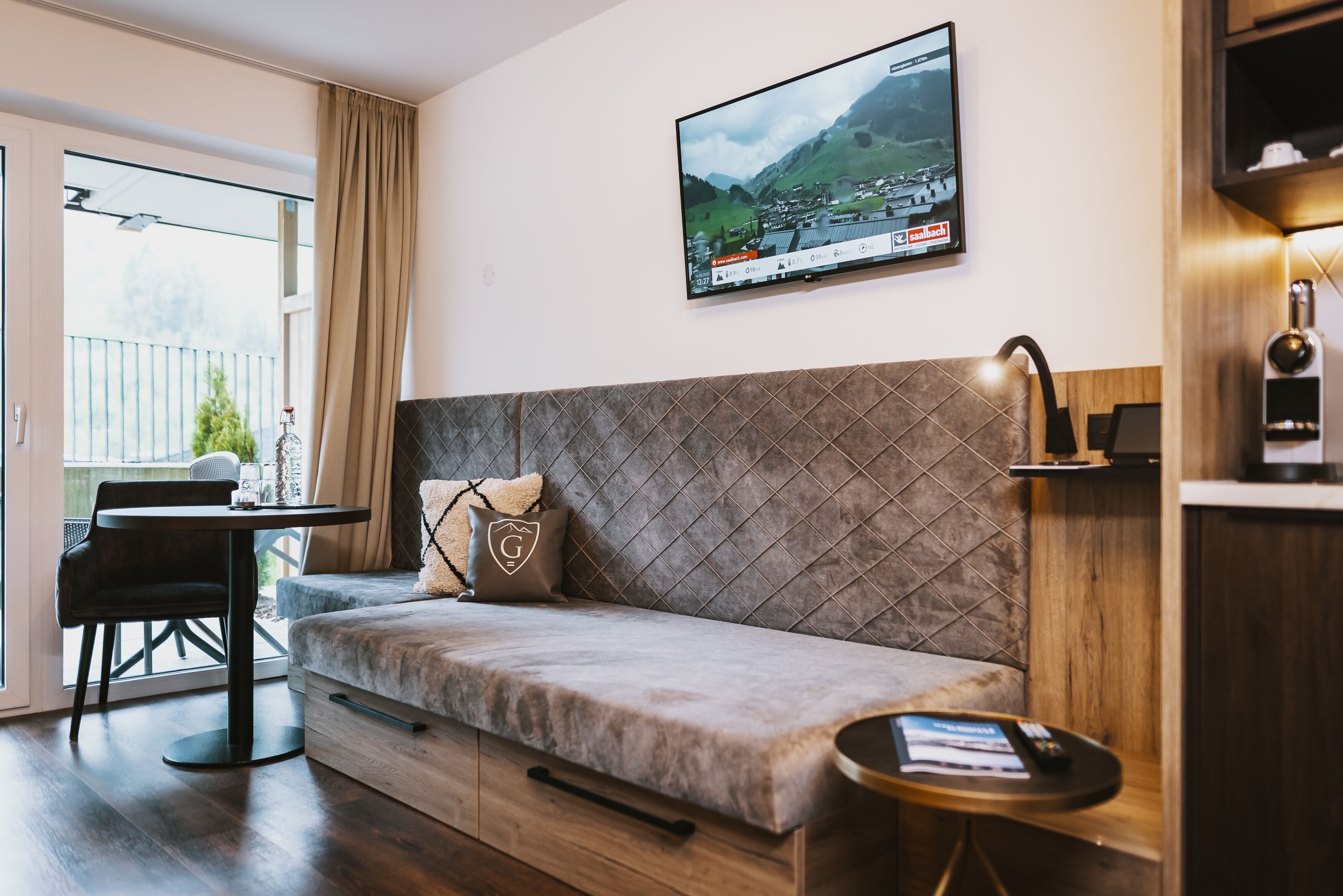 A modern living room with a sofa, a small table, and a TV mounted on the wall.