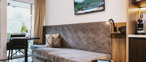 A modern living room with a sofa, a small table, and a TV mounted on the wall.