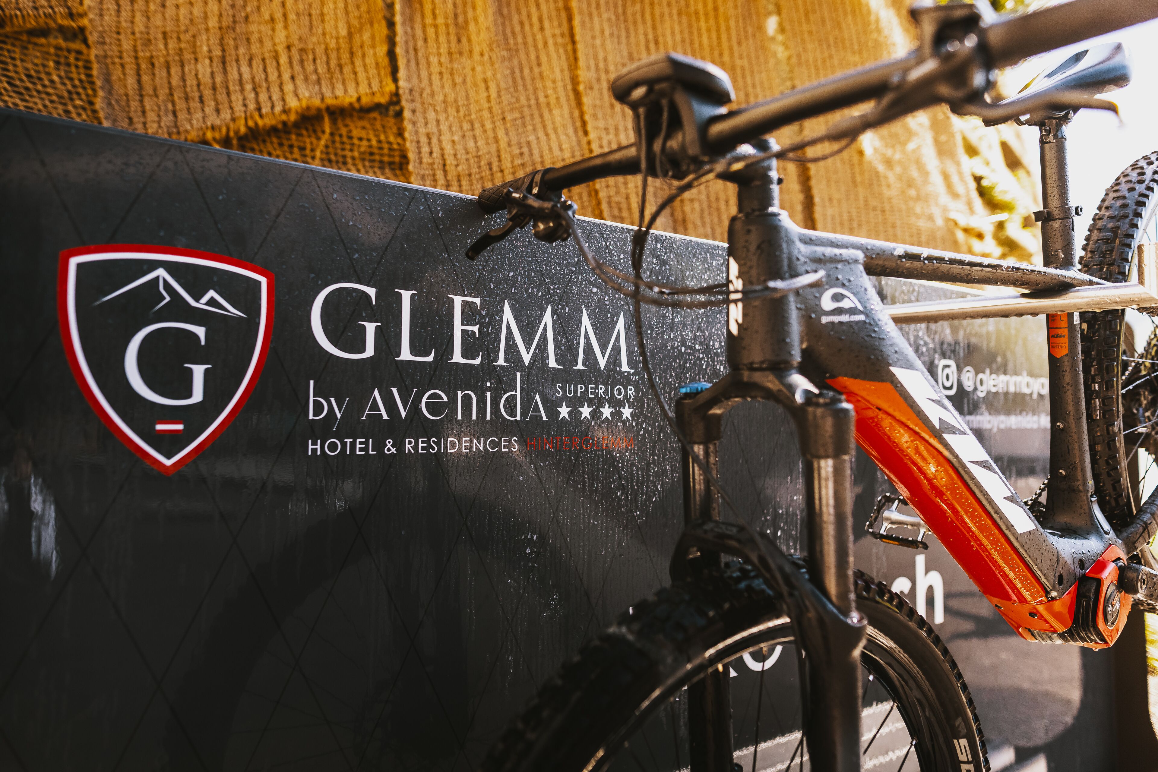 Una bicicleta estacionada frente a un cartel de Glemm by Avenida, que indica un hotel y residencias.