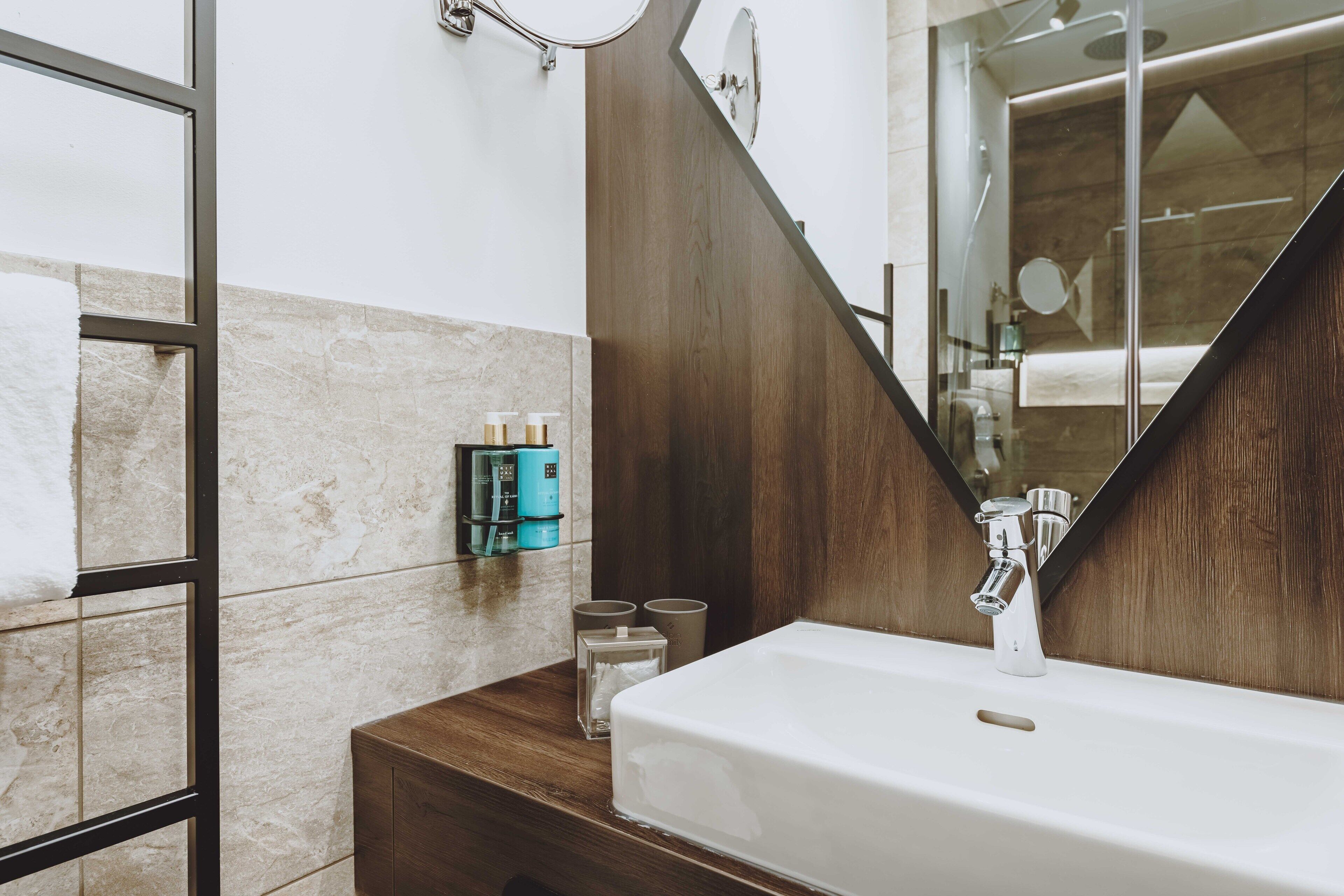 Un bagno moderno con uno specchio grande, un lavandino bianco e un mobile contenitore in legno.