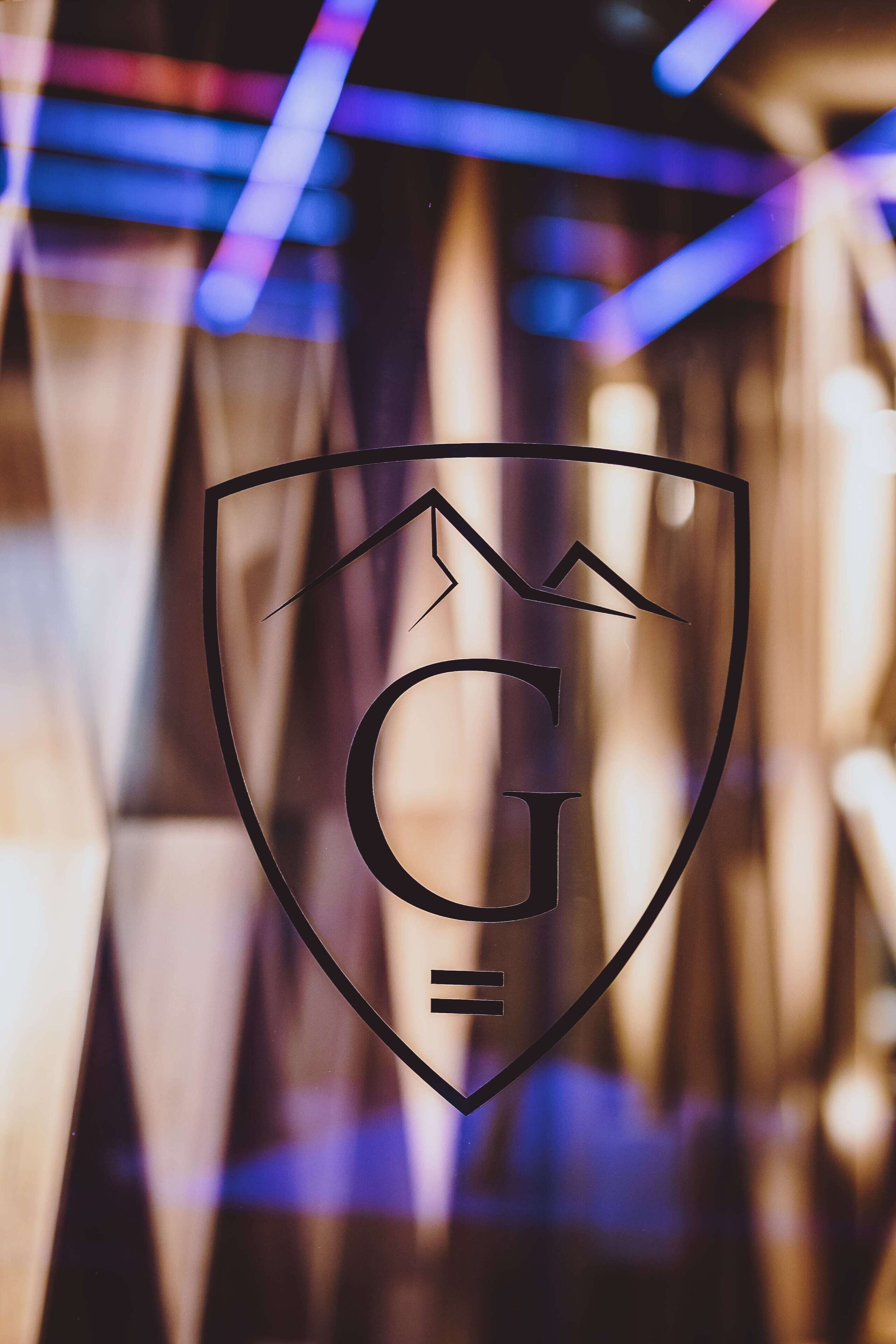 Un logotipo con forma de escudo, la silueta de una montaña y las letras 'G' y 'E'.