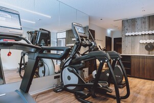 Un gimnasio con equipo de ejercicio, un espejo y una pared de madera con un reloj.