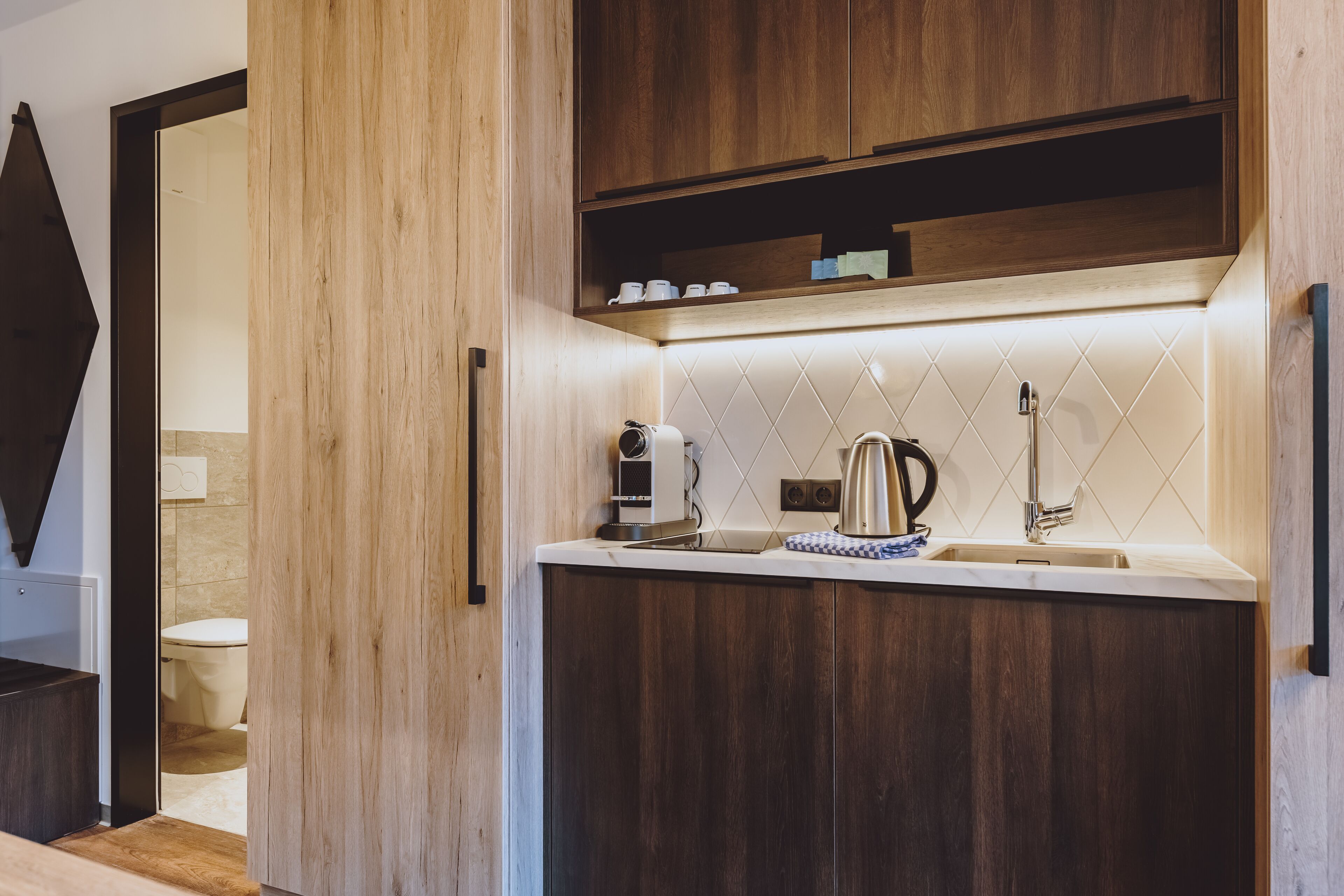 Una cocina moderna con armarios de madera, una encimera, un hervidor y una cafetera.