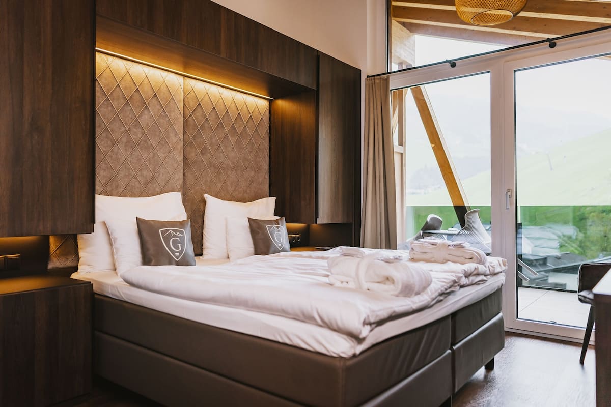 Ein modernes Schlafzimmer mit einem großen Bett, einem Holzkopfende und einer Schiebetür zu einem Balkon.