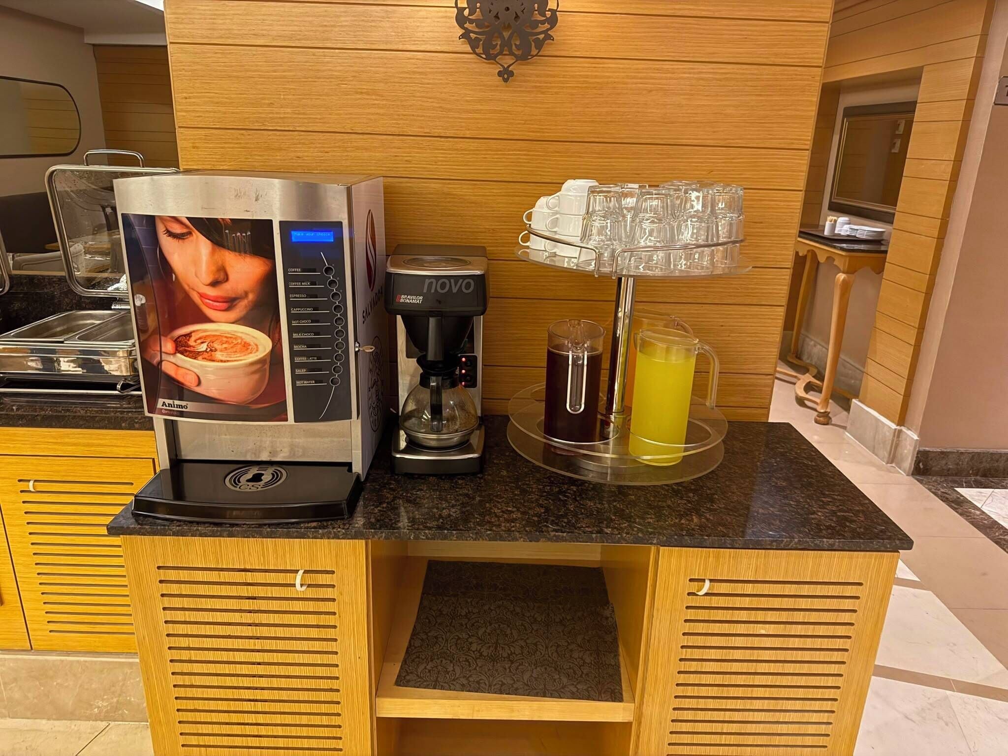 A coffee station with a coffee machine, a coffee dispenser, and a glass of iced coffee.