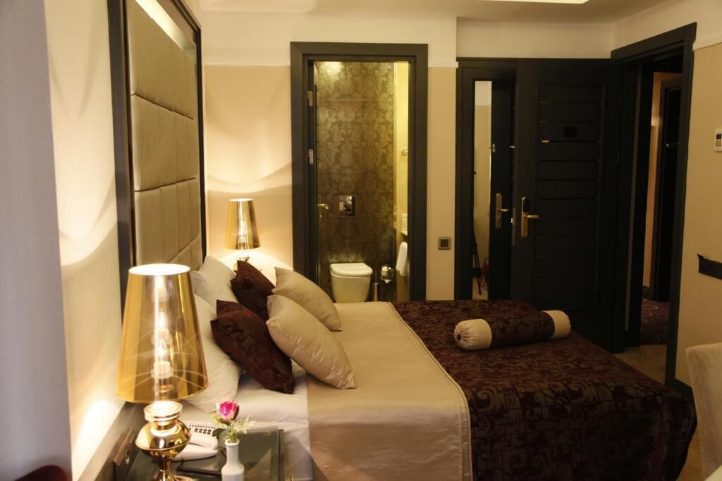 Habitación de hotel con cama, lámpara de noche y espejo.