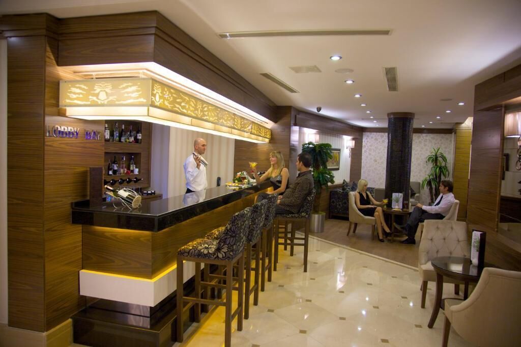A hotel lobby with a bar area, seating arrangements, and a reception desk.