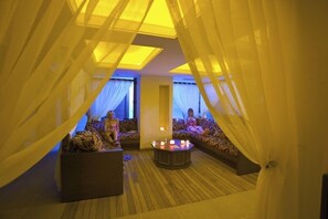 Une pièce accueillante, aménagée comme une tente, avec deux canapés et une table centrale, dotée d’un éclairage doux et de rideaux légers.