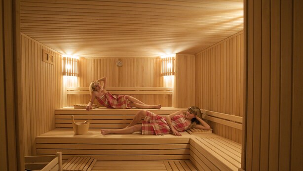 A sauna with wooden benches and benches, a bucket, and a wall-mounted heater. - Mirilayon Hotel (Istanbul)