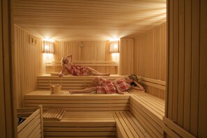 A sauna with wooden benches and benches, a bucket, and a wall-mounted heater. - Mirilayon Hotel (Istanbul)