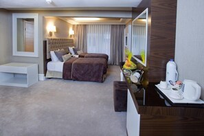 A hotel room with two beds, a bedside table, a mirror, a desk with a coffee maker, and a small seating area. - Mirilayon Hotel (Istanbul)