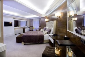 A modern hotel room with a large bed, a bedside table, a mirror, and a television. - Mirilayon Hotel (Istanbul)
