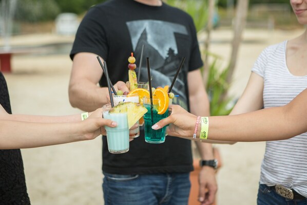 Three people holding drinks with fruit garnishes.