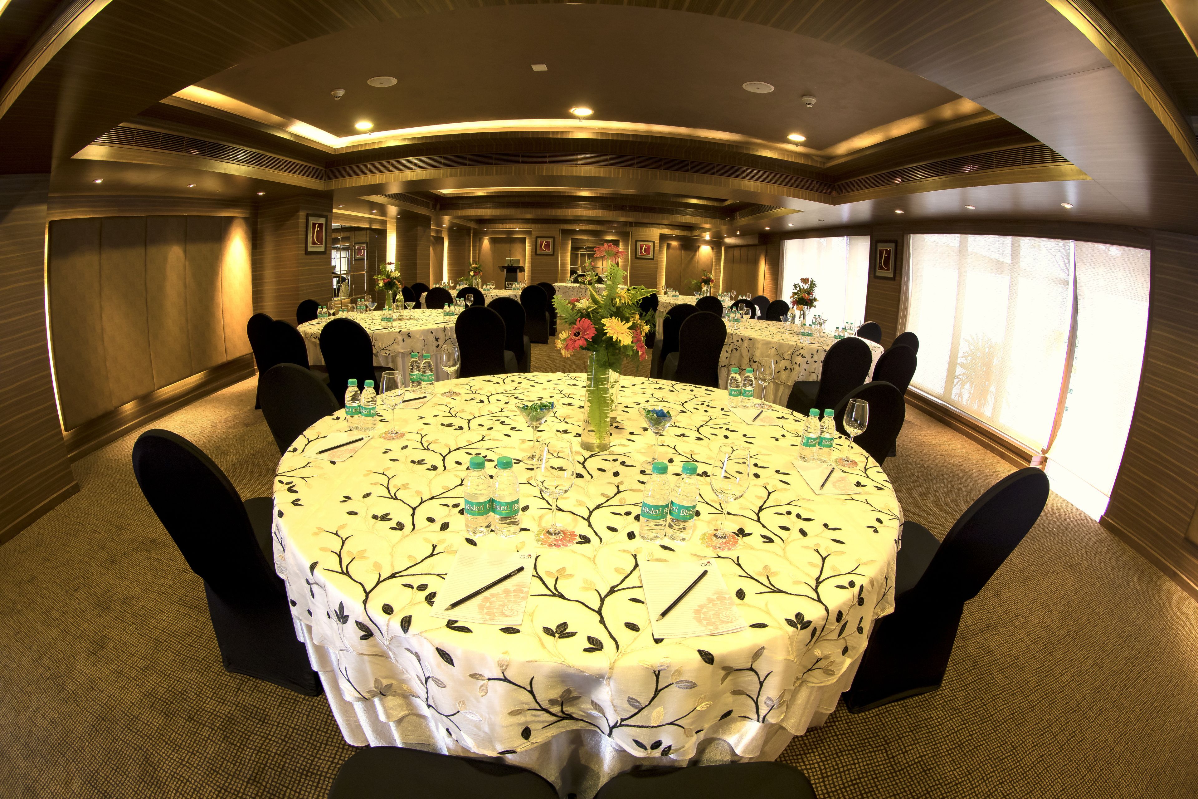 A conference room with round tables, black chairs, and floral tablecloths.