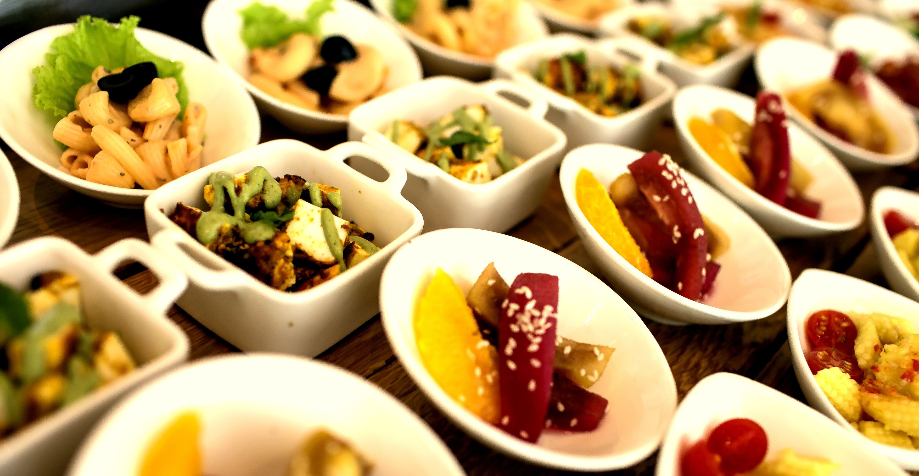 Une variété de plats servis dans de petits bols blancs, sur une table en bois.